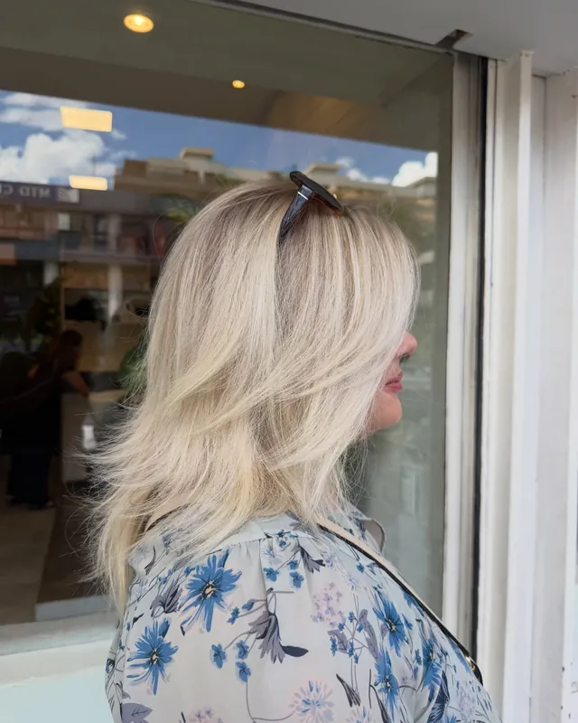 Cabelo loiro liso, visto de perfil, com uma janela ao fundo